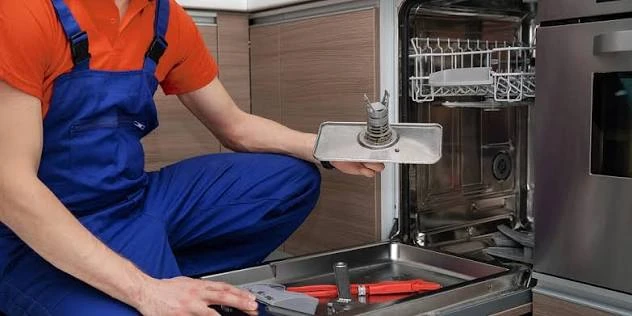 Technician examining the filter of an open dishwasher
